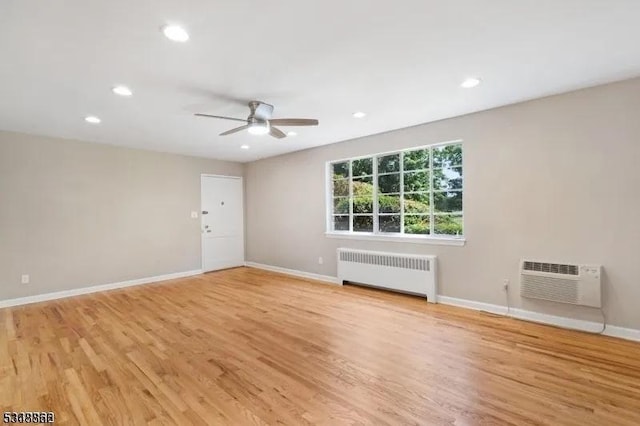 empty room featuring radiator heating unit, ceiling fan, a wall unit AC, baseboards, and recessed lighting