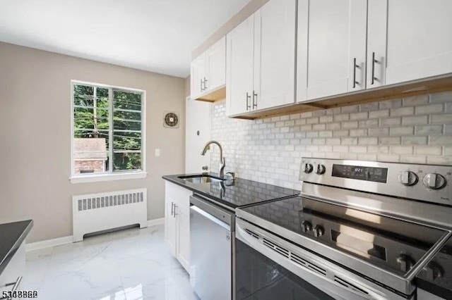 kitchen featuring appliances with stainless steel finishes, radiator, a sink, and white cabinets