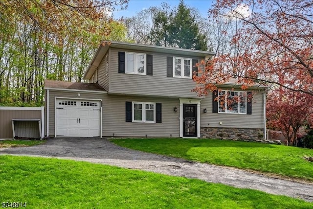 tri-level home featuring an attached garage, a front lawn, and aphalt driveway