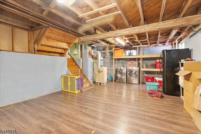unfinished below grade area with freestanding refrigerator, separate washer and dryer, heating unit, and wood finished floors