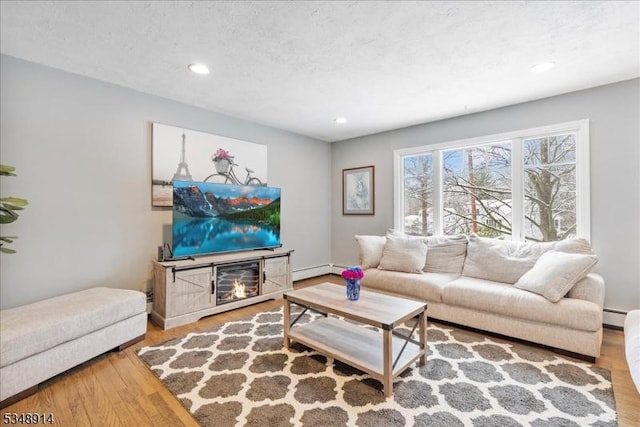 living area featuring a baseboard radiator, recessed lighting, and wood finished floors