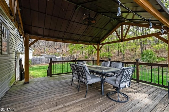 deck with outdoor dining area, a fenced backyard, and a yard