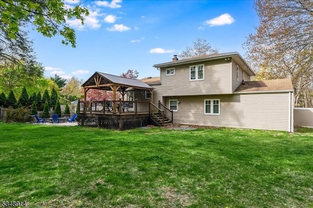 back of property with fence, a deck, a chimney, a gazebo, and a yard