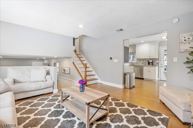 living area with stairs, recessed lighting, visible vents, and light wood finished floors
