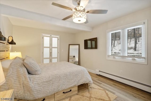 bedroom with wood finished floors, beamed ceiling, baseboards, baseboard heating, and a ceiling fan