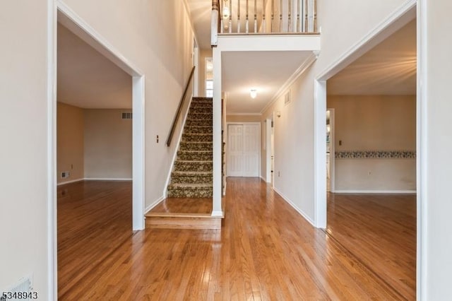 foyer featuring stairway, baseboards, wood finished floors, and visible vents
