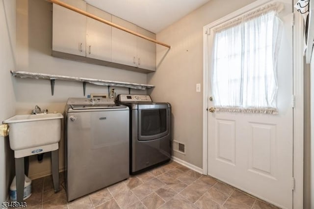 clothes washing area featuring baseboards, visible vents, cabinet space, and washer and clothes dryer