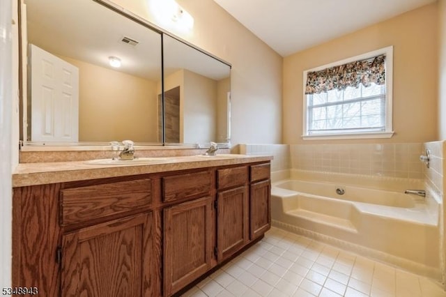 full bath with a sink, double vanity, tile patterned floors, visible vents, and a garden tub