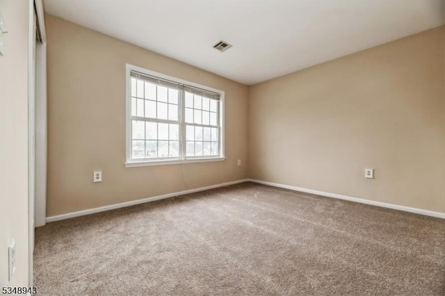 carpeted spare room featuring baseboards and visible vents
