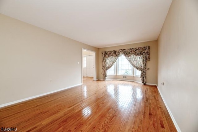 empty room featuring baseboards and light wood finished floors