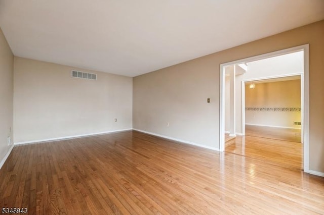 empty room featuring visible vents, light wood finished floors, and baseboards