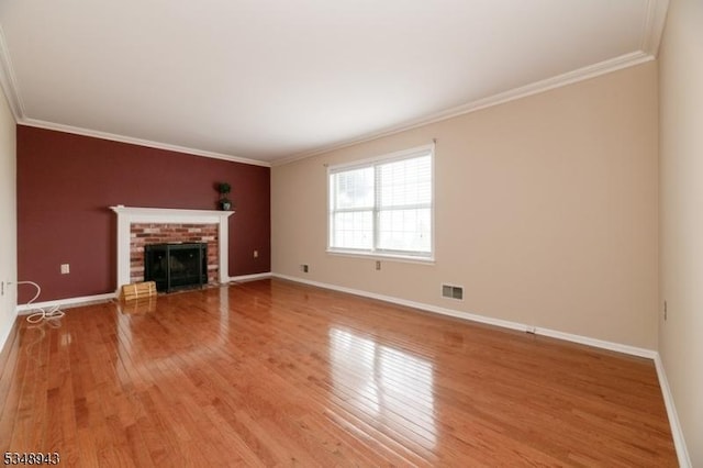 unfurnished living room featuring baseboards, visible vents, ornamental molding, and light wood-style flooring