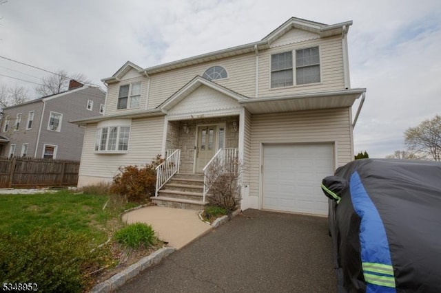 view of front of property with a garage, aphalt driveway, and fence