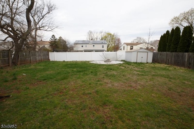 view of yard with a storage shed, a fenced backyard, and an outdoor structure