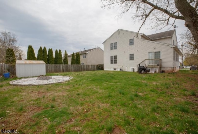view of yard with a fenced backyard, an outdoor structure, a fire pit, and a shed