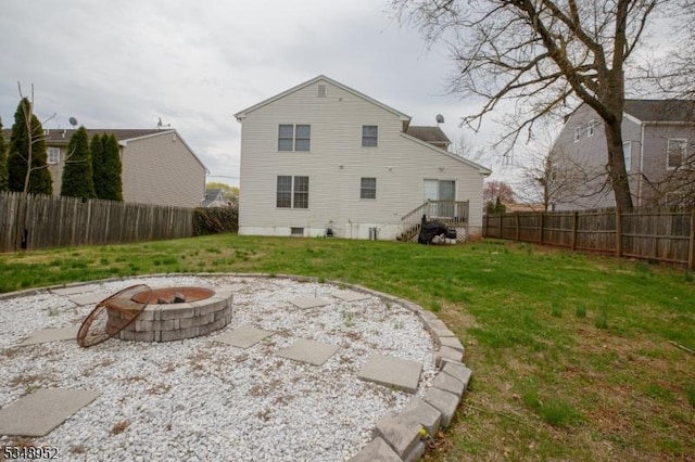 rear view of house featuring a fire pit, a fenced backyard, and a lawn