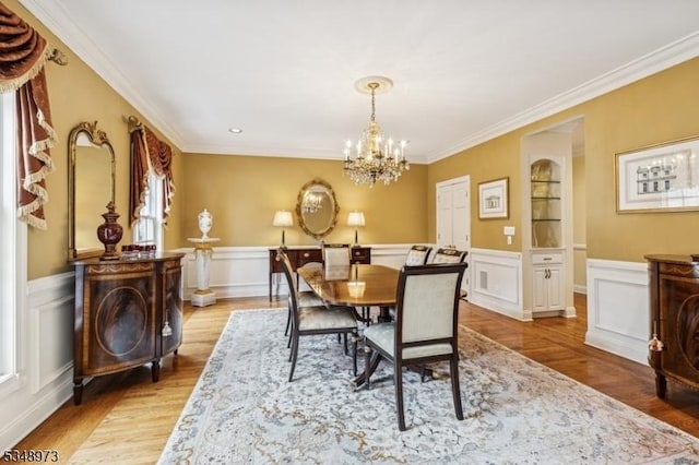 2 Queens Ct, Mendham Twp, NJ 07960 - dining space featuring crown molding, a chandelier, light wood finished floors, wainscoting, and a decorative wall