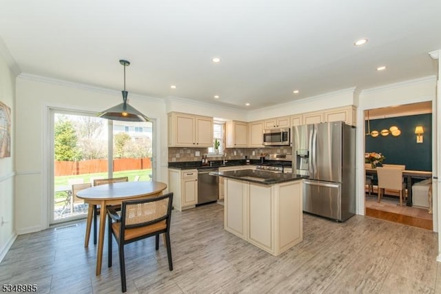 kitchen featuring stainless steel appliances, cream cabinetry, dark countertops, a center island, and backsplash
