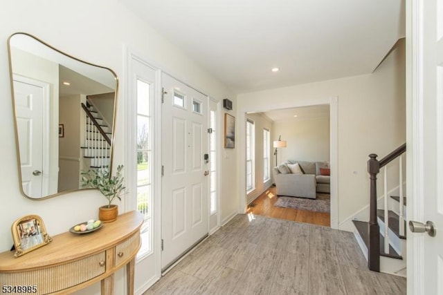 entrance foyer featuring stairs, healthy amount of natural light, light wood-type flooring, recessed lighting, and baseboards