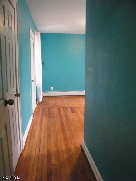 hall featuring baseboards, a baseboard radiator, and wood-type flooring