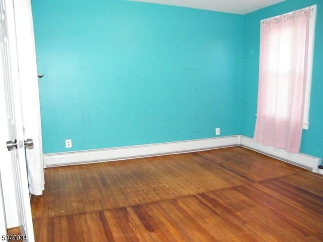 unfurnished room with baseboards and hardwood / wood-style flooring