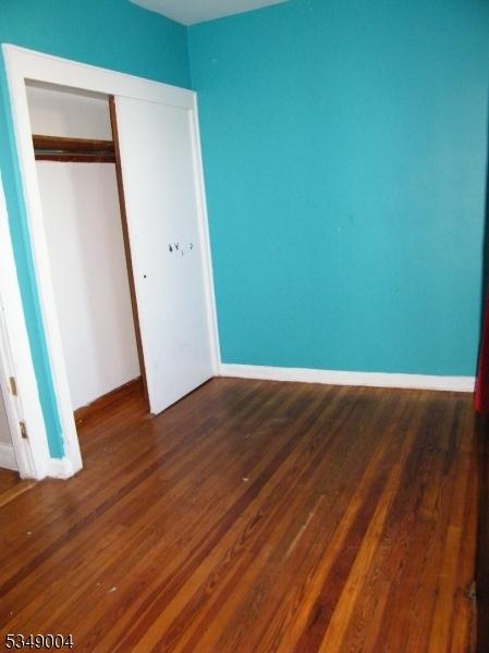 unfurnished bedroom featuring baseboards, dark wood finished floors, and a closet