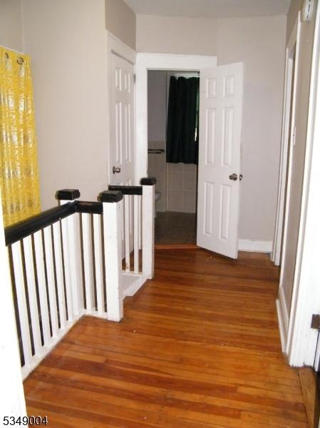 hallway with wood finished floors and an upstairs landing