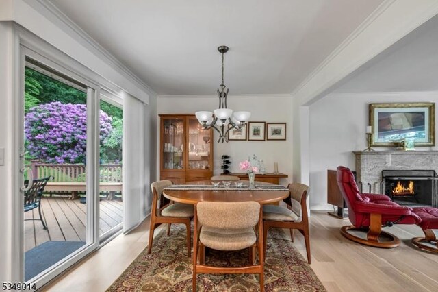 84 Burnham Pkwy, Morris Twp, NJ 07960 - dining area featuring light wood finished floors, a chandelier, ornamental molding, and a warm lit fireplace