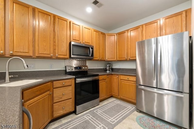 kitchen featuring a sink, dark countertops, stainless steel appliances, and visible vents