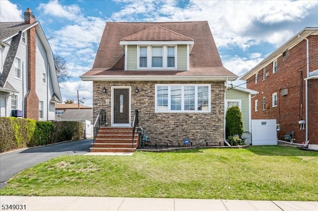 view of front of house featuring a front yard, stone siding, and a shingled roof