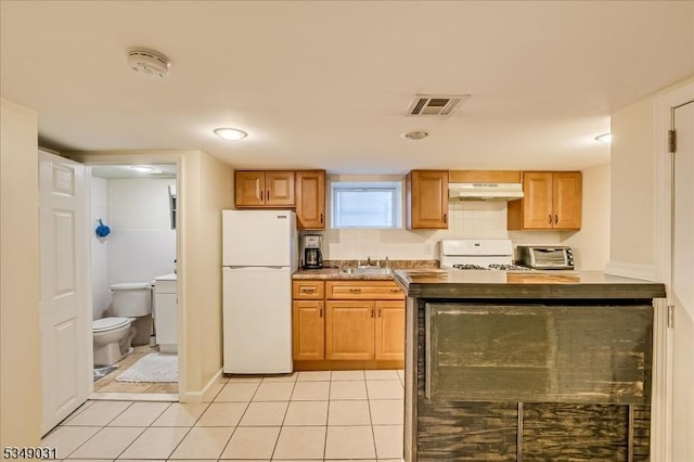 kitchen featuring visible vents, a sink, white appliances, under cabinet range hood, and light tile patterned flooring