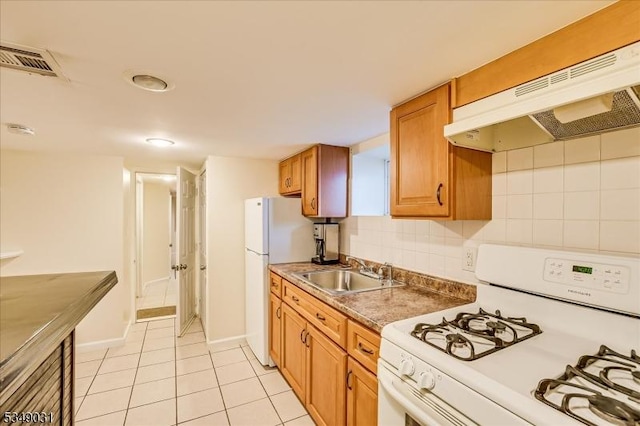 kitchen with white appliances, visible vents, under cabinet range hood, a sink, and brown cabinets