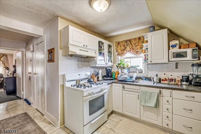 kitchen with white cabinetry, under cabinet range hood, a sink, and white appliances