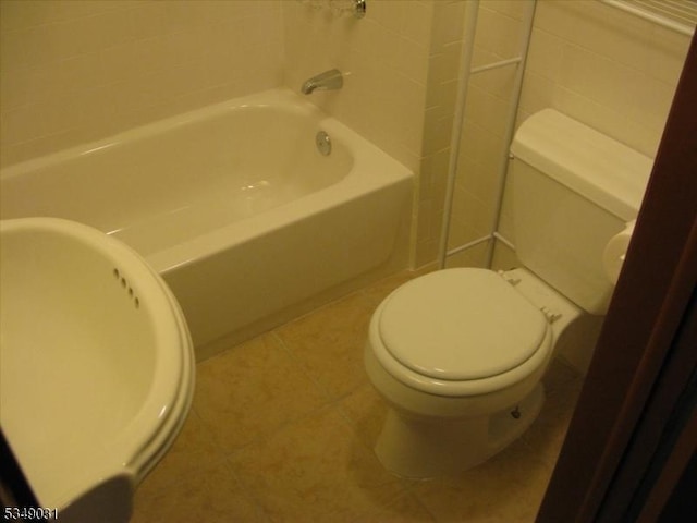bathroom with tile patterned floors, a bath, and toilet