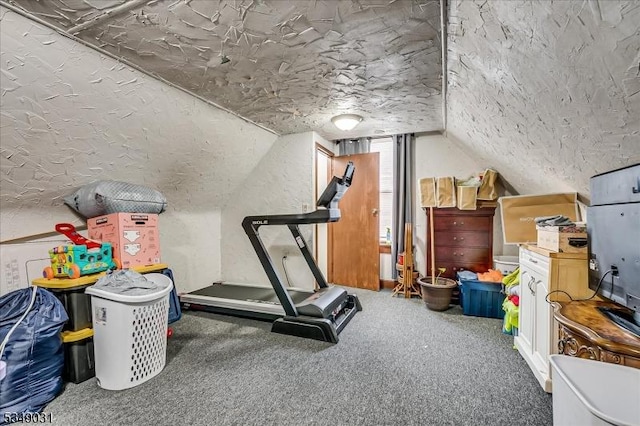 exercise area with carpet floors, vaulted ceiling, a textured wall, and a textured ceiling