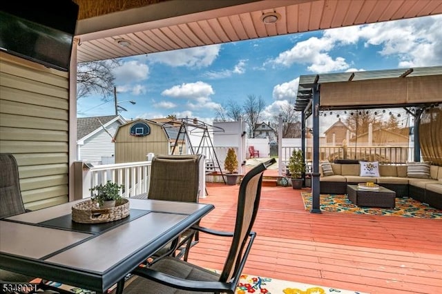 wooden deck featuring outdoor lounge area, an outdoor structure, outdoor dining area, fence, and a storage unit