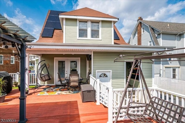 exterior space with french doors, a wooden deck, and solar panels