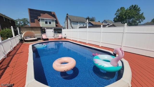 view of swimming pool with a fenced backyard, a wooden deck, and a fenced in pool