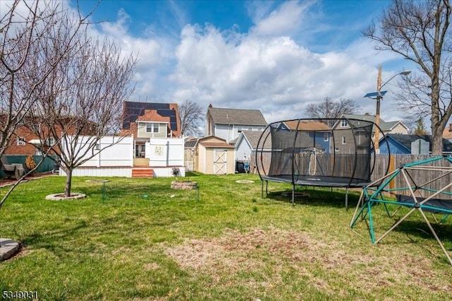 view of play area with a shed, an outdoor structure, fence, a trampoline, and a residential view