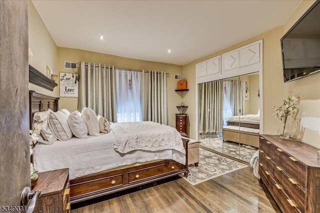 bedroom with access to outside, wood finished floors, and visible vents
