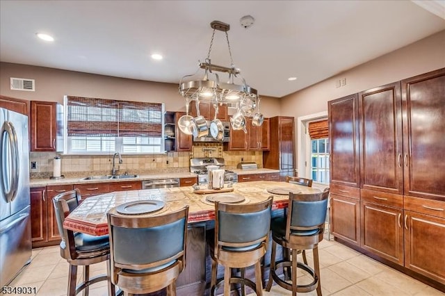 kitchen with a wealth of natural light, visible vents, a sink, stainless steel appliances, and a breakfast bar area