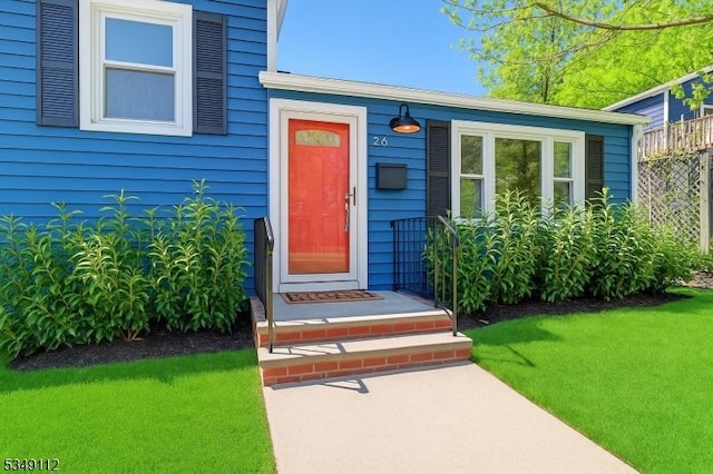 doorway to property with fence and a yard