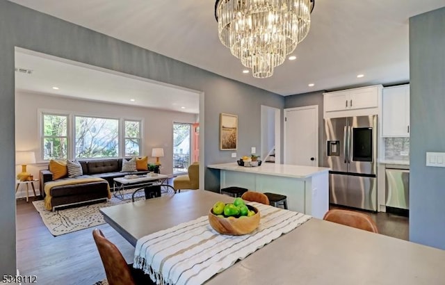 dining area with visible vents, recessed lighting, wood finished floors, and a notable chandelier