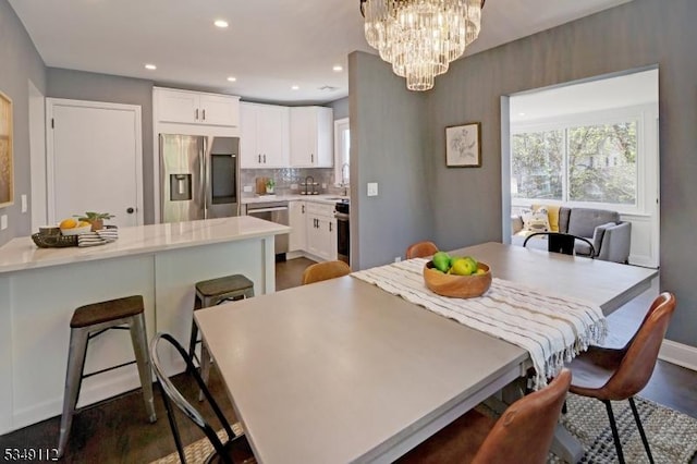 dining space featuring recessed lighting, baseboards, dark wood-style floors, and a notable chandelier