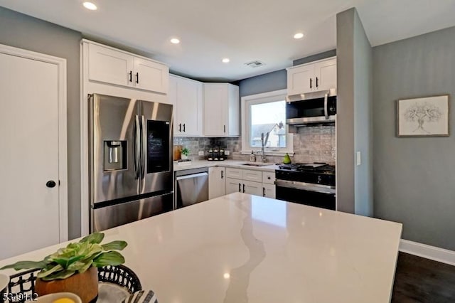 kitchen with backsplash, appliances with stainless steel finishes, a sink, recessed lighting, and white cabinetry