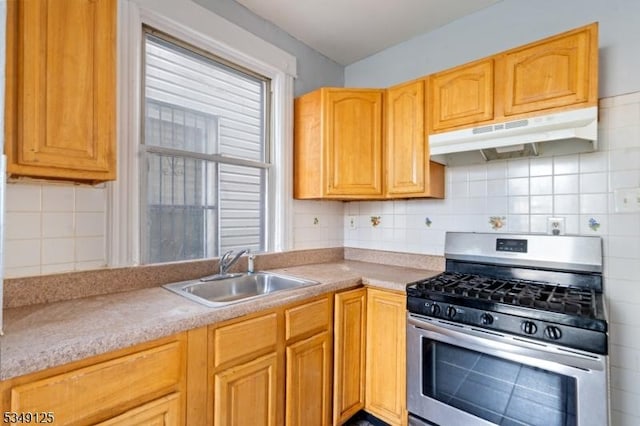 kitchen with decorative backsplash, stainless steel gas range, light countertops, under cabinet range hood, and a sink