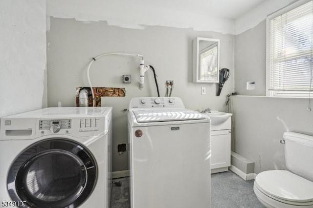 clothes washing area with separate washer and dryer, laundry area, and a sink