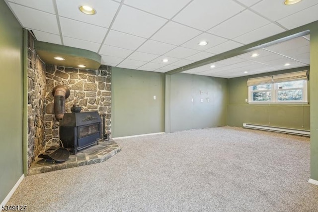 basement featuring a baseboard heating unit, a wood stove, recessed lighting, and carpet