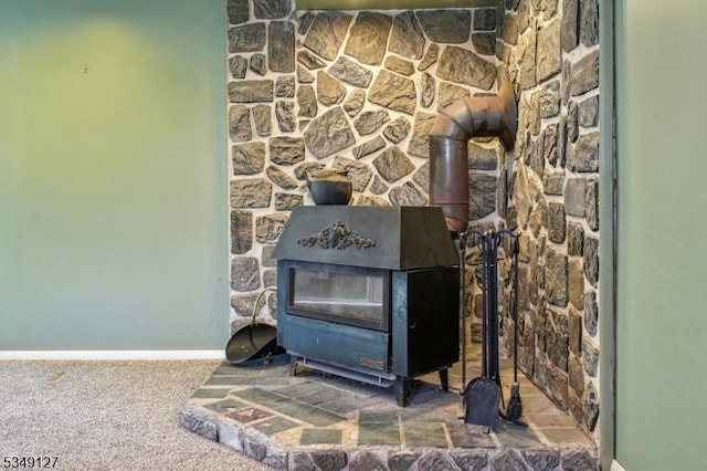 room details with baseboards, a wood stove, and carpet floors