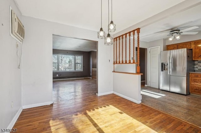 interior space featuring brown cabinets, wood finished floors, stainless steel refrigerator with ice dispenser, ceiling fan, and baseboards